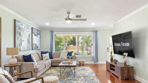 A living room with a sofa, coffee table, TV, and artwork on the wall. - 2 miles to Beach~ Pool ~Cabana~ Pool Table (Deerfield Beach)