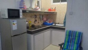 Cocina compacta con microondas, refrigerador y lavamanos. Hay una ventana con vistas al exterior.