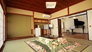 A tatami mat room with a floral bed, a piano, and a traditional Japanese room layout. - Kaemon Ryokan (Takahama)