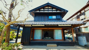 A traditional Japanese house with a tiled roof, wooden structure, and a small porch. - Kaemon Ryokan (Takahama)