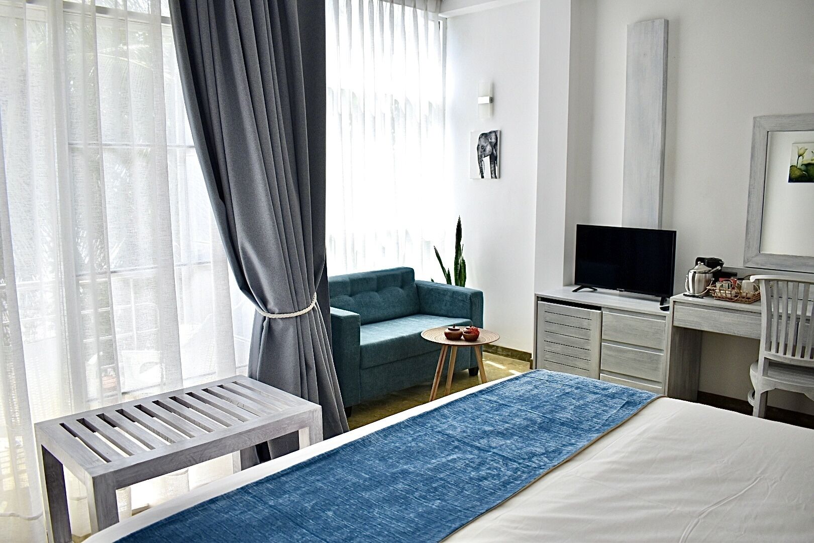 Una camera d'albergo moderna con un letto, una scrivania, una televisione e un tavolino con una pianta.