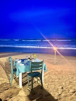 A table set for two on a beach with a view of the ocean.
