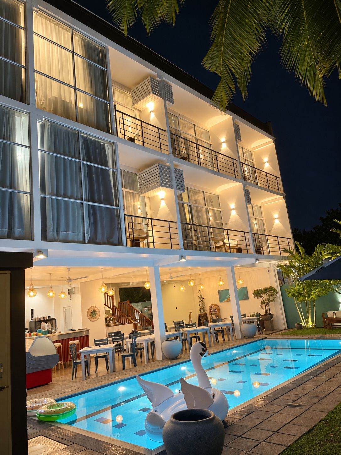 Ein mehrstöckiges Hotel mit Schwimmbad, Außenbereich und einem gut beleuchteten Balkon.