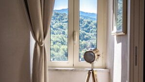 Una stanza con finestra, tende, un treppiede con una luce e un letto.