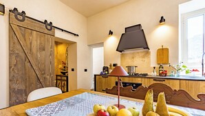 Una cucina con un tavolo di legno, una ciotola di frutta e una porta a graticcio scorrevole.
