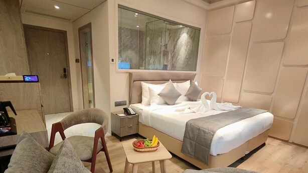 A modern hotel room with a bed, a desk, a chair, and a small table with fruit. - Maxxvalue Hotel MIDC (Mumbai)