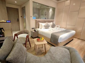 Una habitación de hotel moderna con una cama, un escritorio, una silla y una pequeña mesa con fruta.