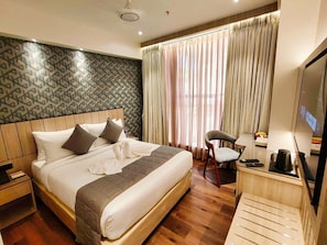 Una habitación de hotel con una cama grande, un escritorio con televisor y una silla.