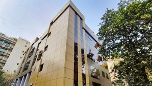 A modern building with a reflective glass facade and a prominent vertical stripe design. - Maxxvalue Hotel MIDC (Mumbai)