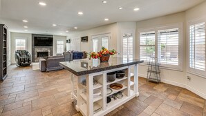 A spacious living area with a fireplace, a seating area, and a kitchen island with storage shelves. - Walk to State Farm Stadium! Poolside Desert Escape (Glendale)