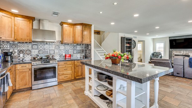 A modern kitchen with wooden cabinets, a built-in oven, and a granite countertop island. - Walk to State Farm Stadium! Poolside Desert Escape (Glendale)