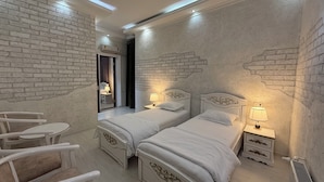 Habitación de hotel con dos camas, una mesita y una silla.