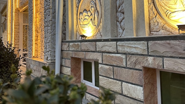 Un edificio con fachada de piedra y relieves iluminados.