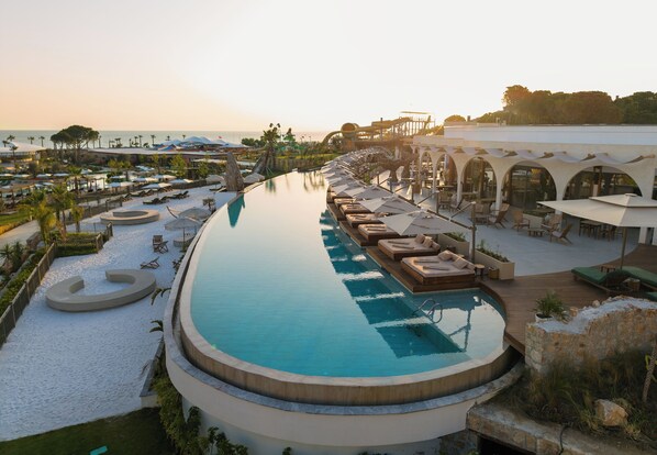 Un resort con una amplia piscina infinita, zonas de estar al aire libre y vistas al océano.