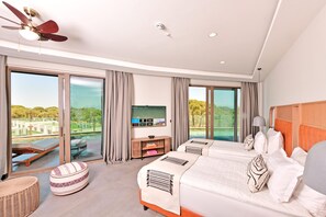 A modern hotel room with a large bed, a television, and a view of a golf course through the sliding glass doors. - Ethno Belek (Serik)