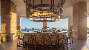 A circular bar with a marble countertop and wooden chairs, overlooking a coastal view. - Ethno Belek (Serik)