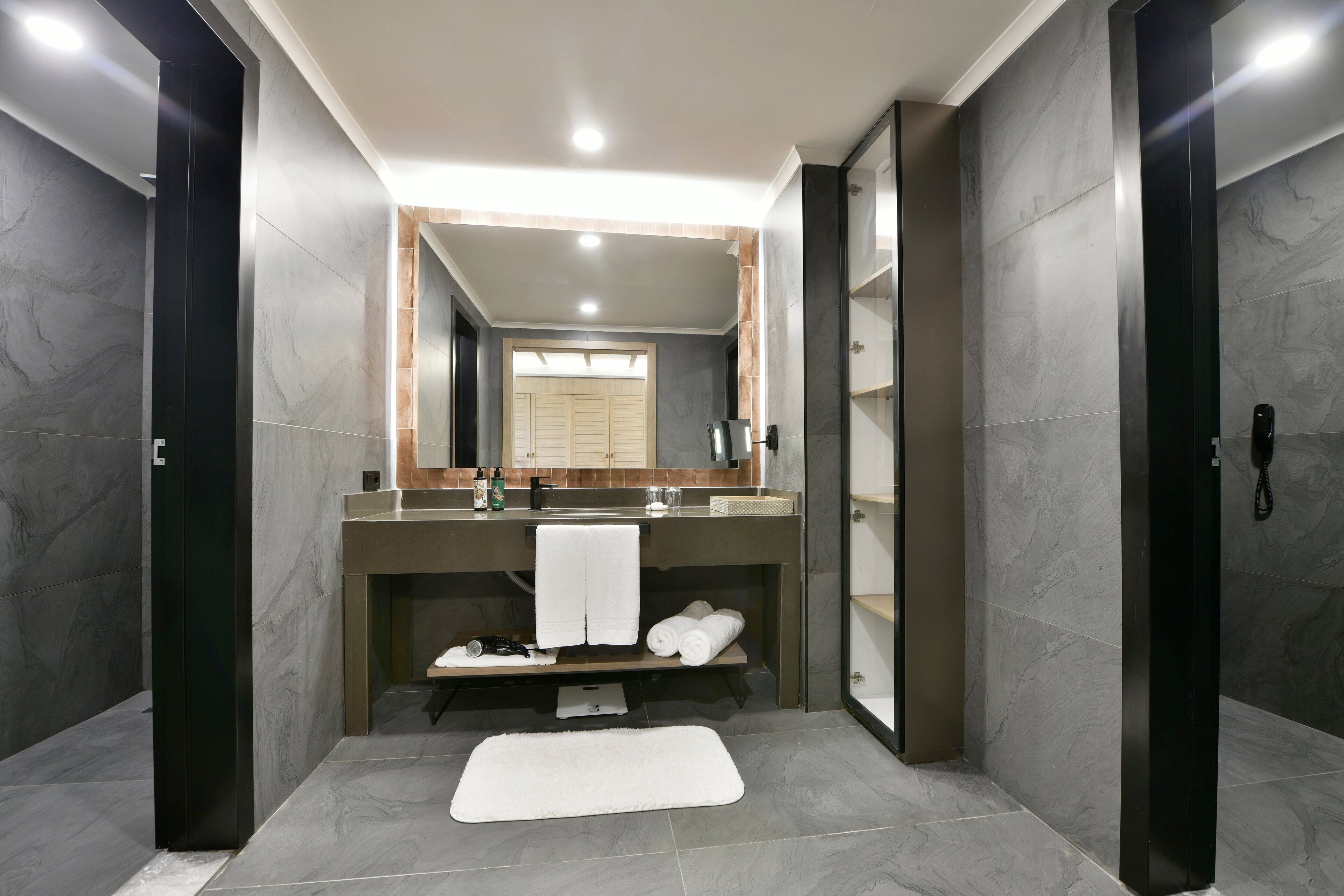 A modern bathroom with a large mirror, a sink, and a towel rack.