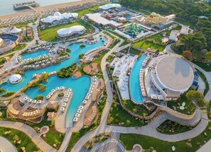 Vista aérea de un resort con varias piscinas, un edificio circular grande y un parque acuático.