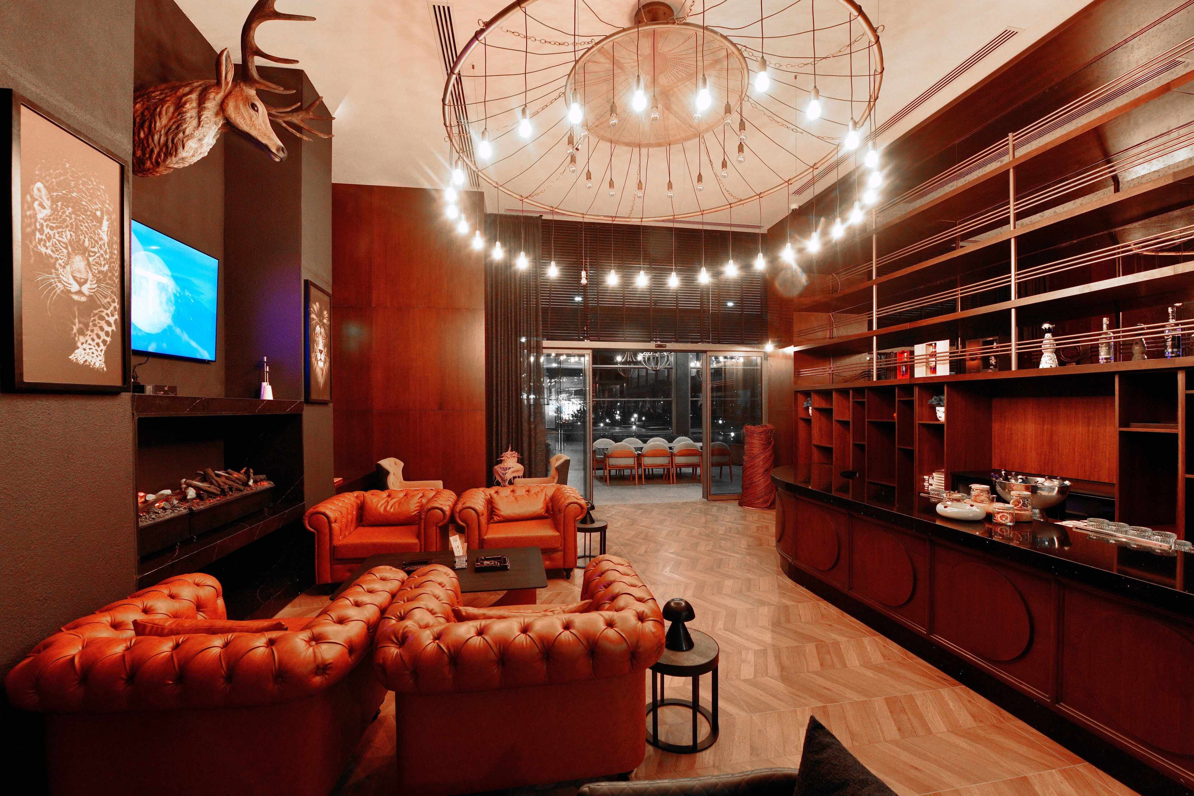 Un intérieur moderne avec un ensemble de canapés en cuir, un téléviseur et un lustre.