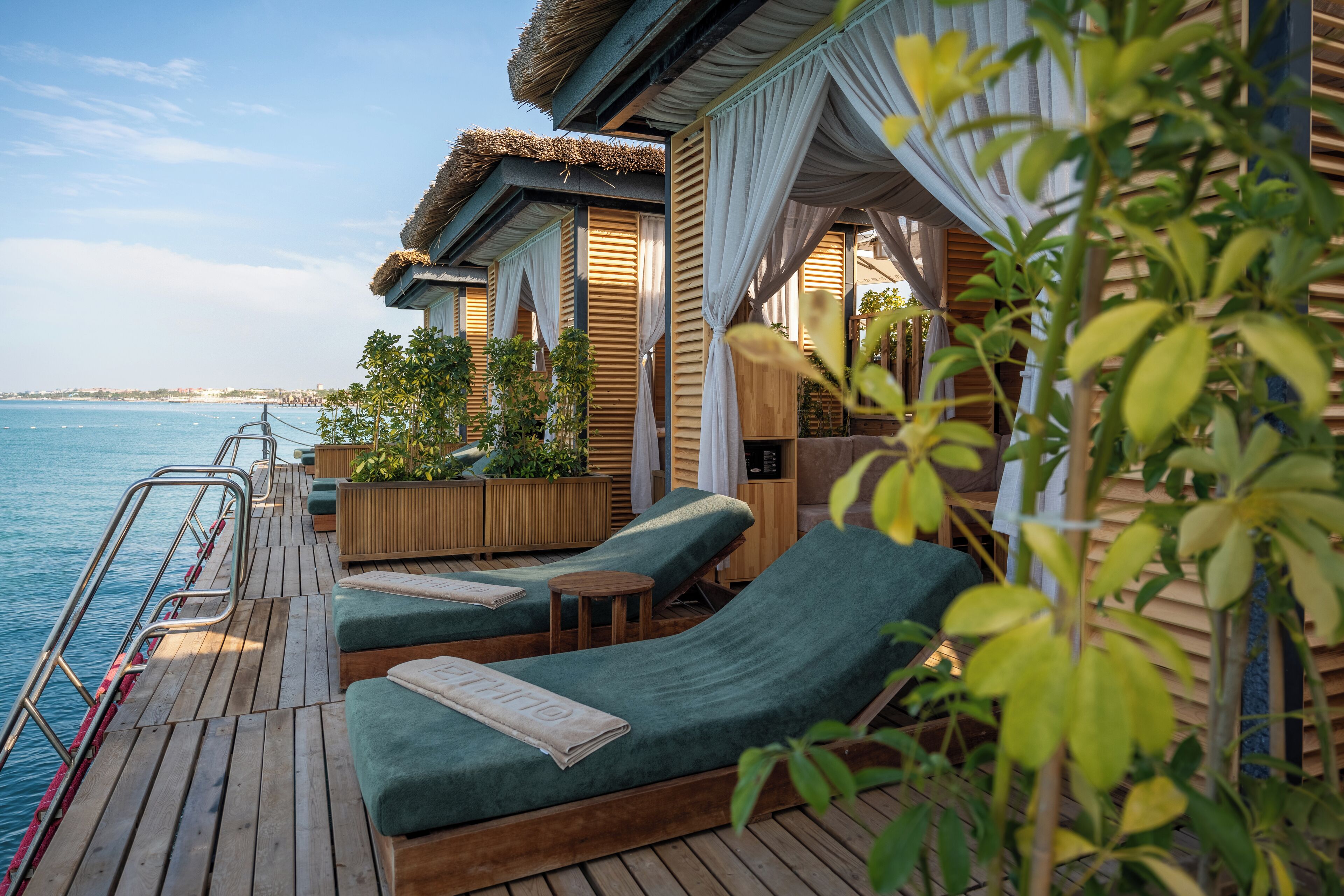 A wooden deck with two lounge chairs, a small table, and a wooden cabinet.