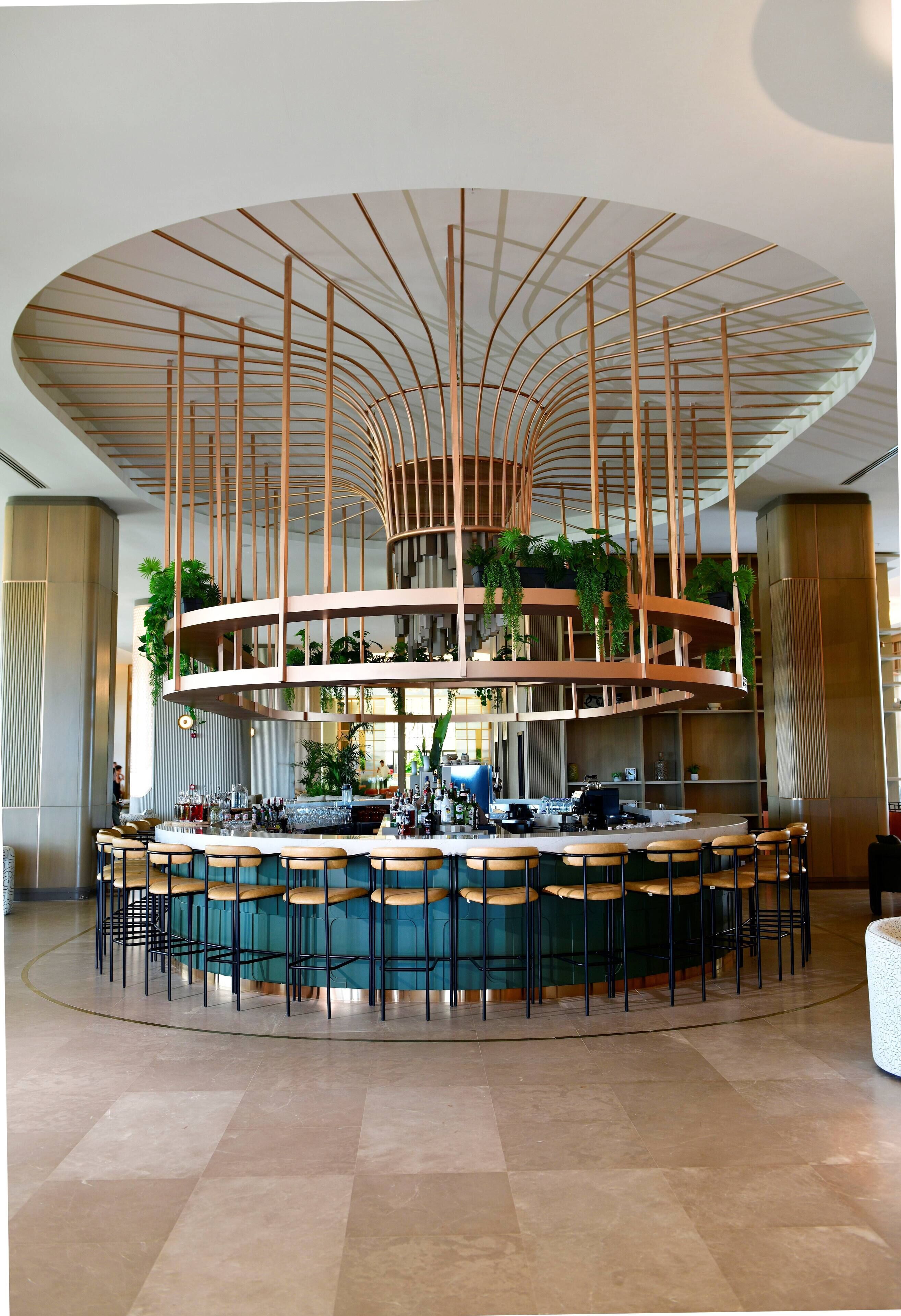 A modern bar area with a circular layout, multiple seating options, and a central column with plants.