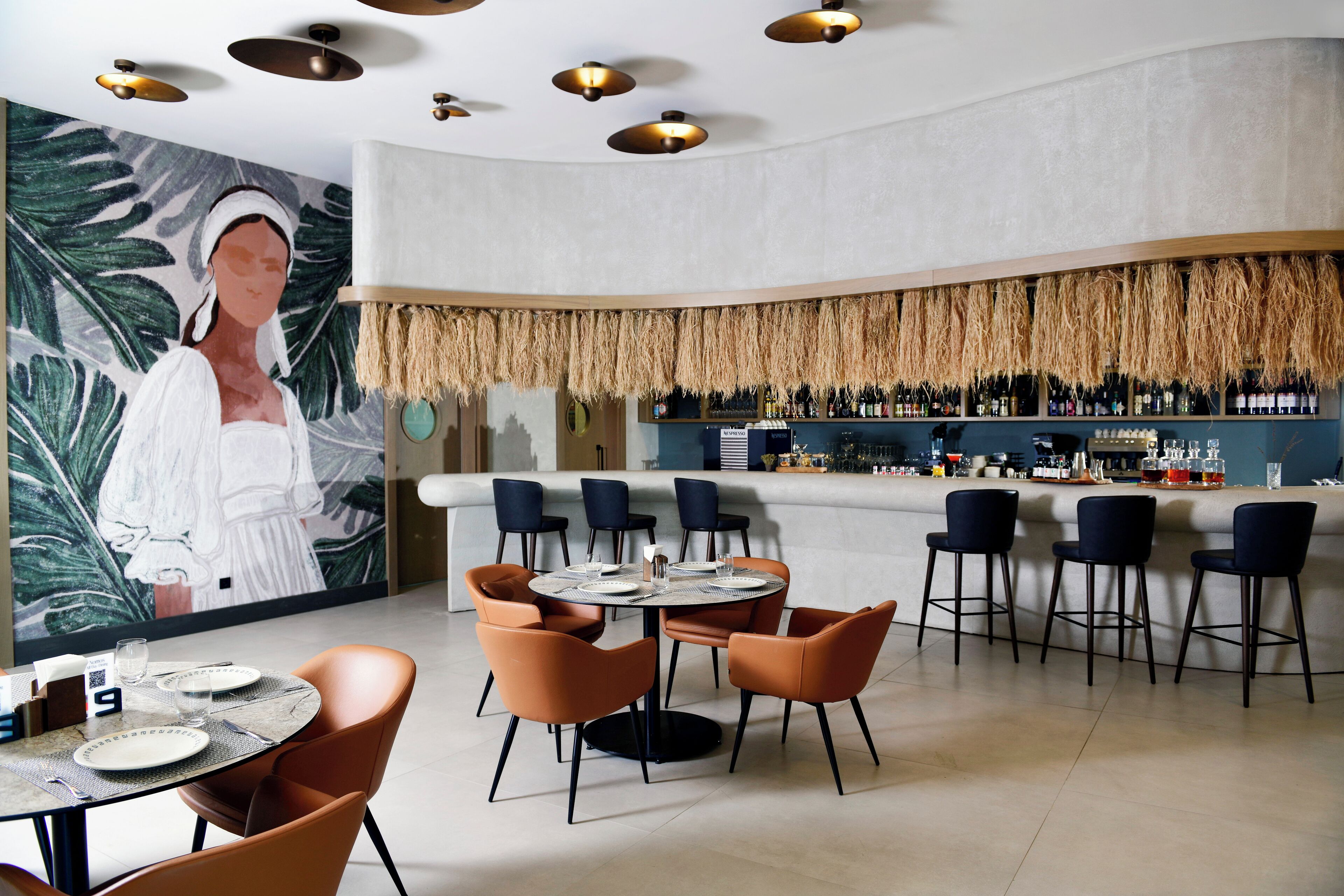 Un restaurant doté d’un bar, de tables rondes et de chaises.