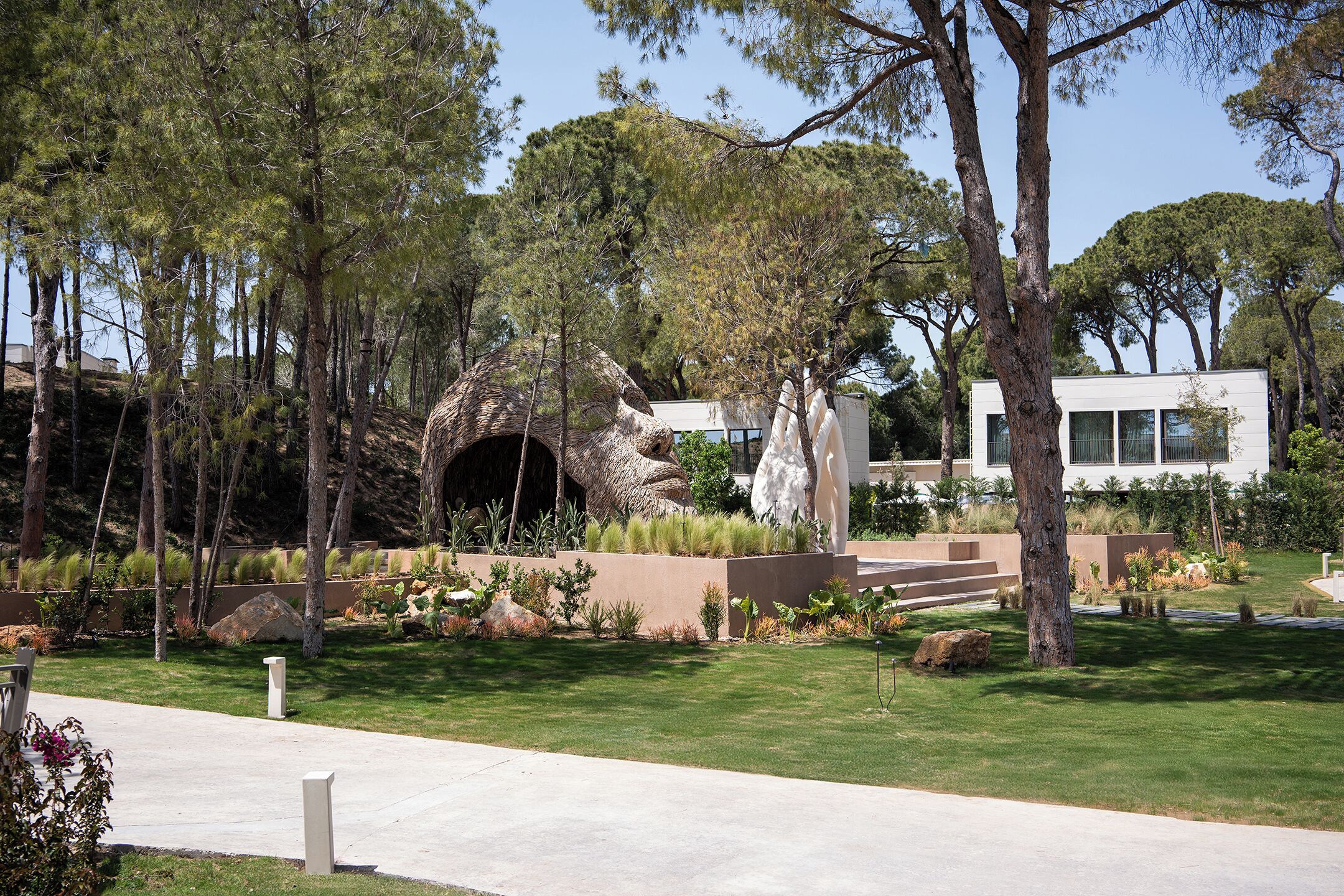 Ein modernes Gebäude mit minimalistischem Design, umgeben von einem angelegten Garten mit verschiedenen Pflanzen und Bäumen.