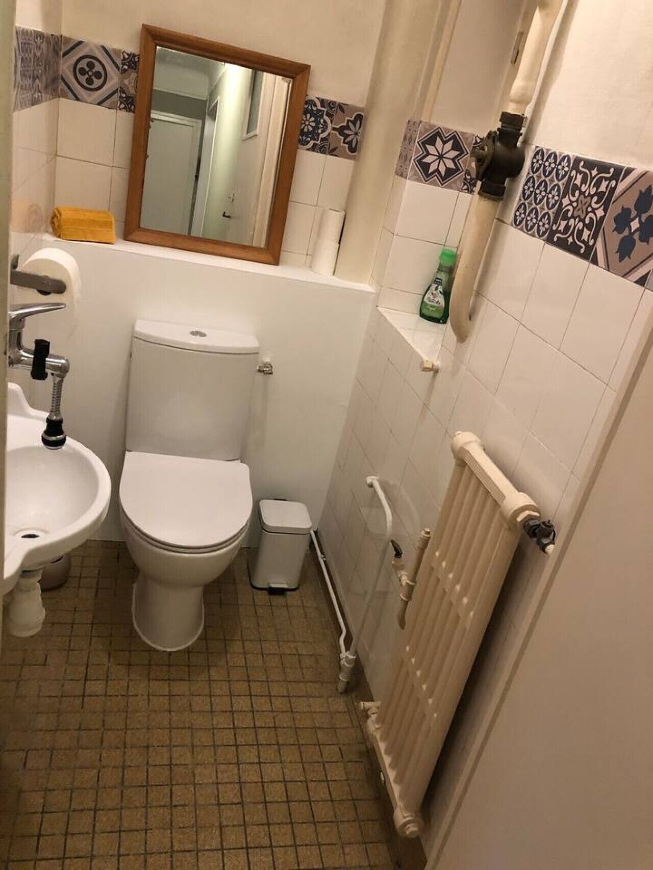A compact bathroom with a toilet, sink, and radiator.
