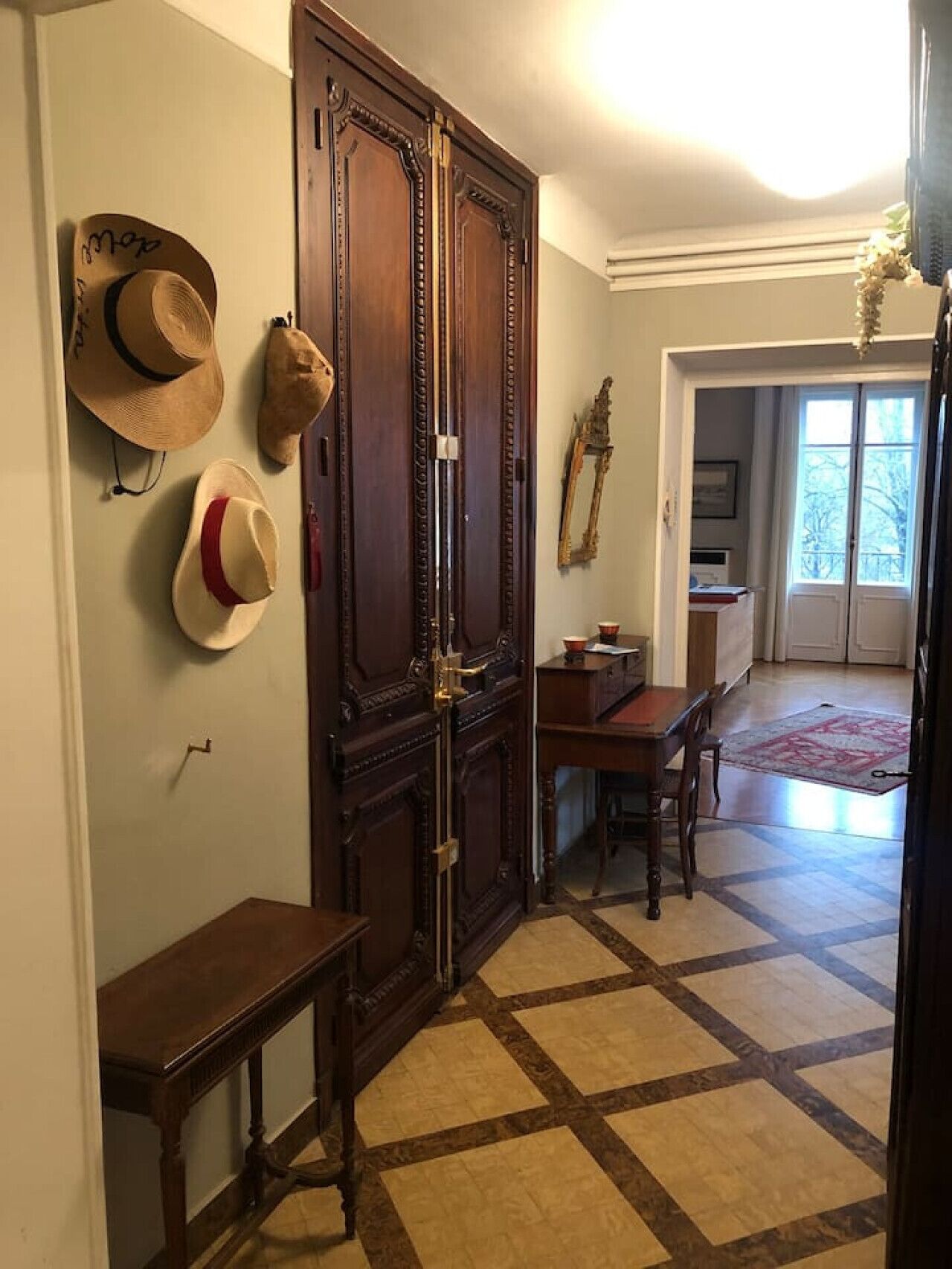 Ein Zimmer mit Schachbrettfußboden, einer Holztür und einem Esstisch mit Stühlen.