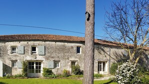 A stone building with a curved roof, multiple windows with shutters, and a well-maintained garden. - Cottage (sleeps 6) at Domaine de Chantageasse, a 17th century estate with pool (Asnières-la-Giraud)