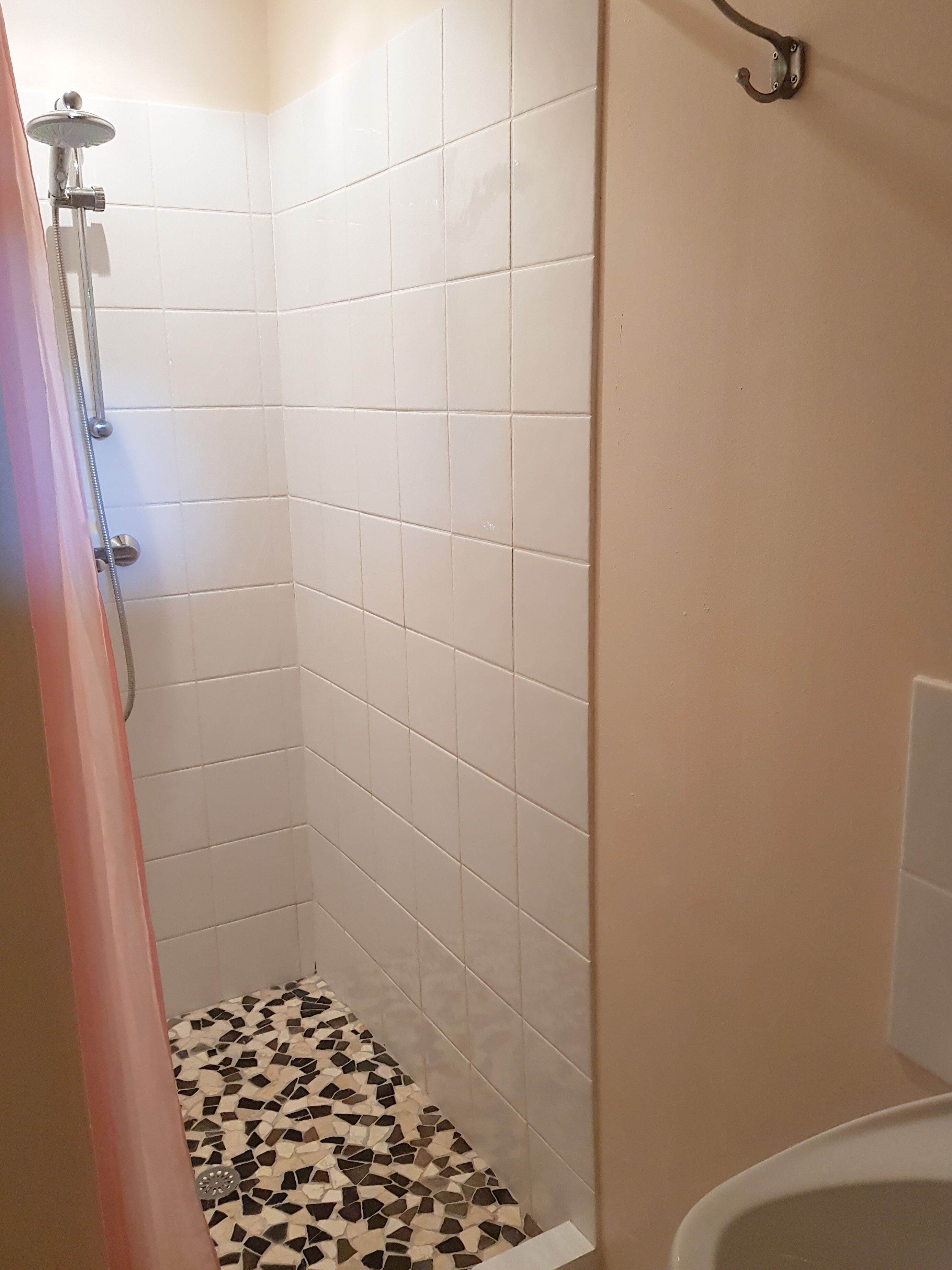 A small, tiled bathroom with a shower area, a toilet, and a sink.