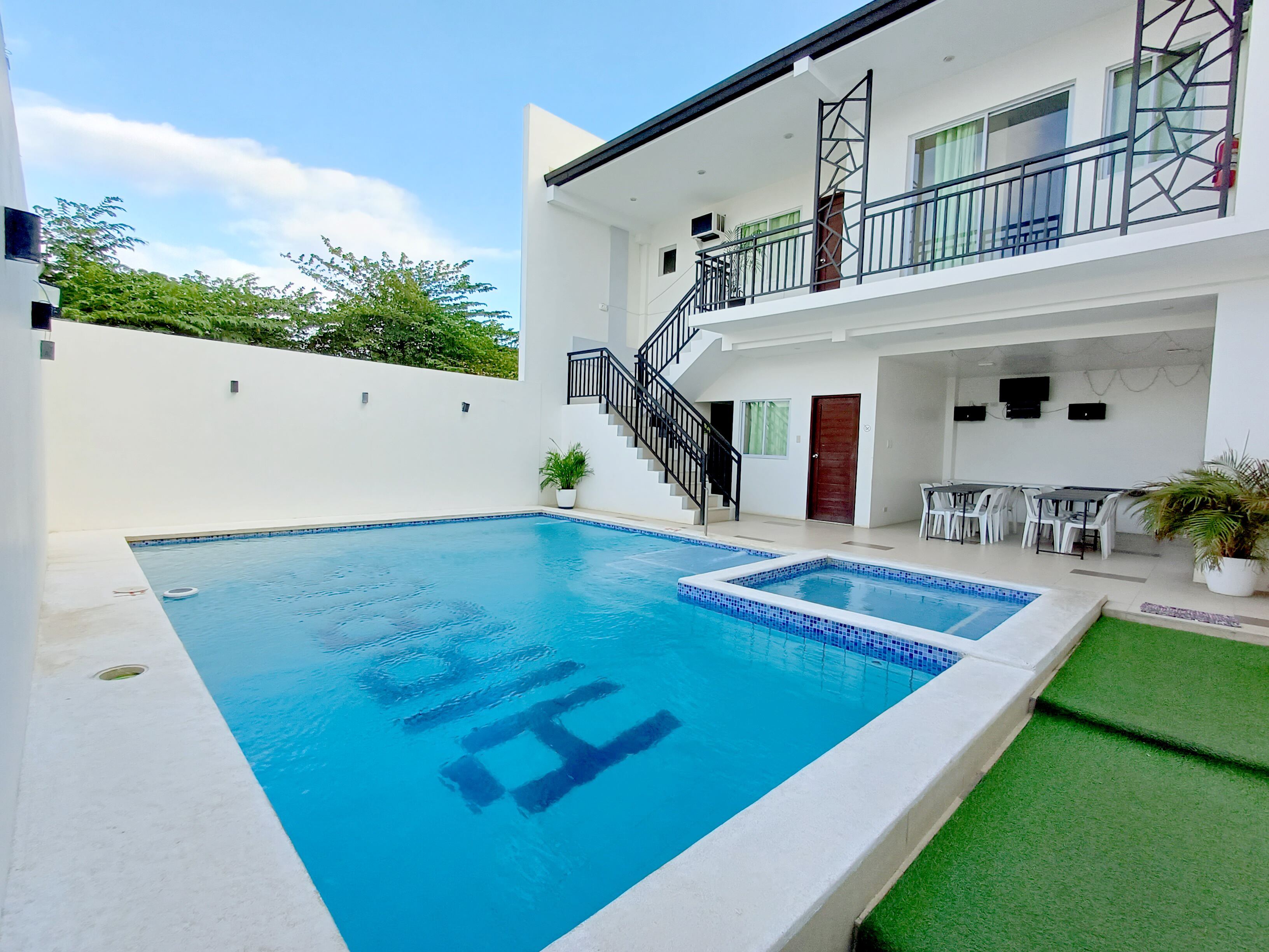 A modern two-story house with a swimming pool, outdoor seating, and a staircase.