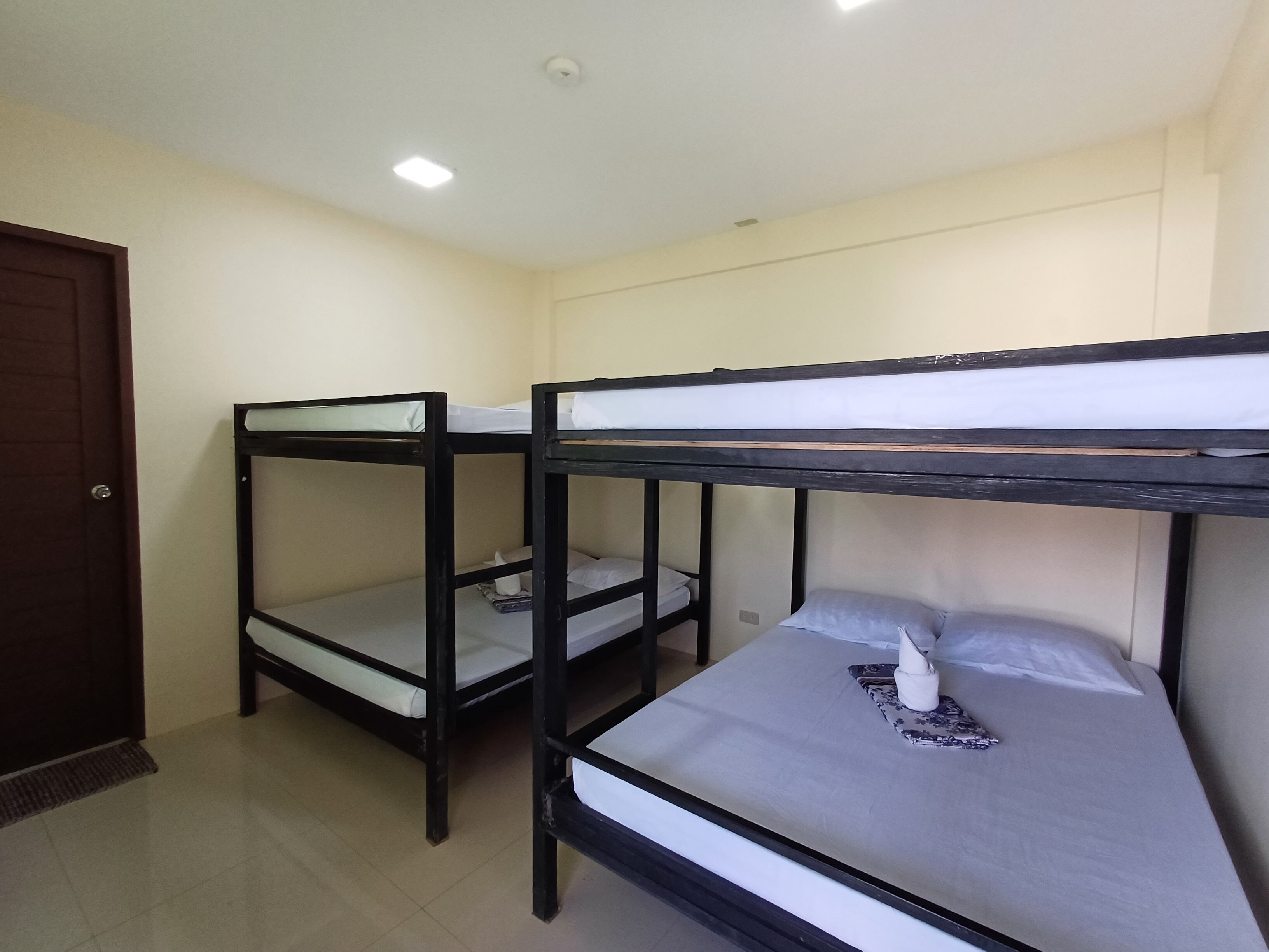 A room with two bunk beds, a door, and a ceiling light.