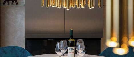 Un comedor moderno con una mesa de mármol, dos sillas, una botella de vino y un elemento decorativo en la pared.