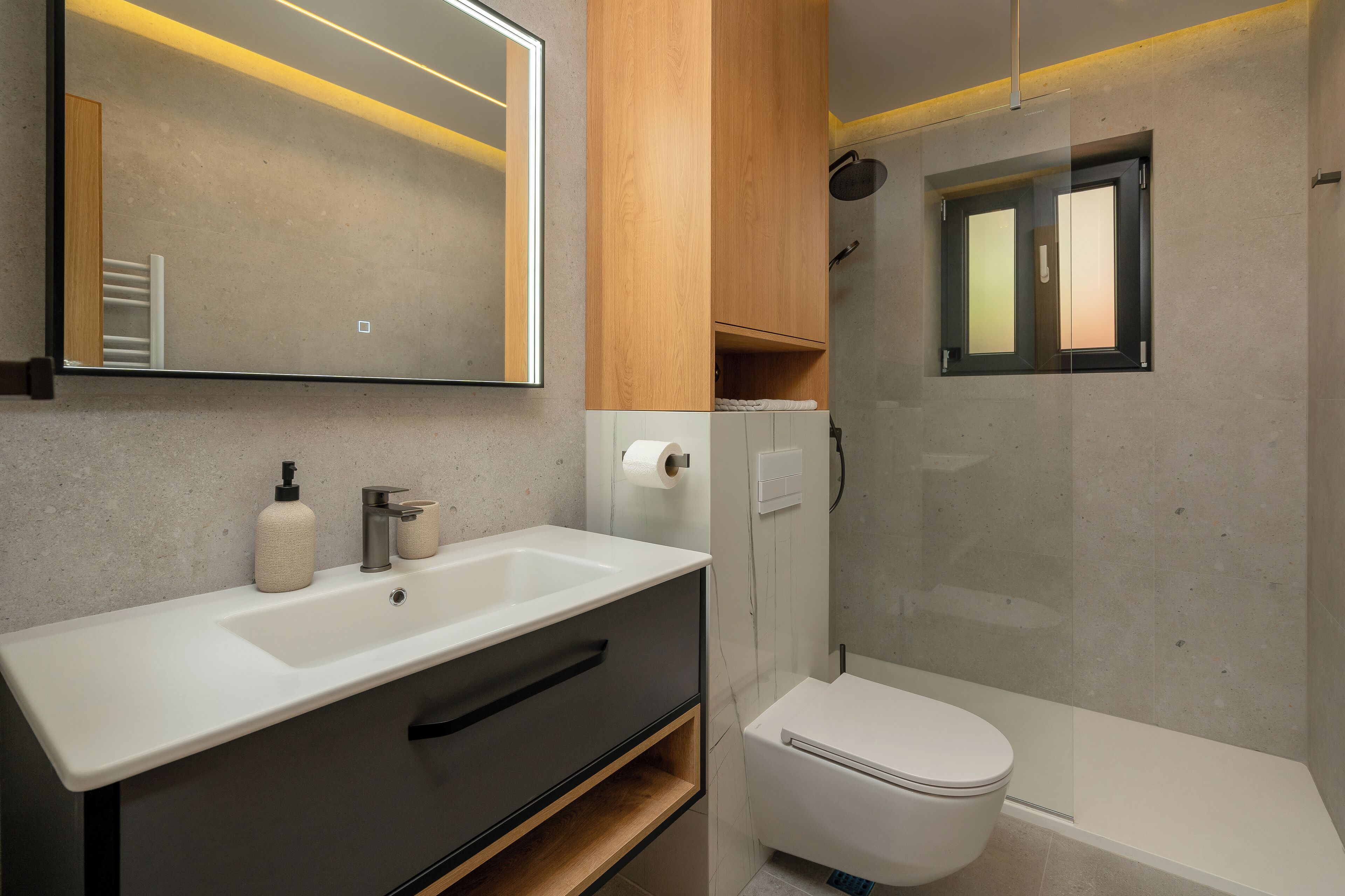 A modern bathroom with a white sink, a toilet, and a shower enclosure.