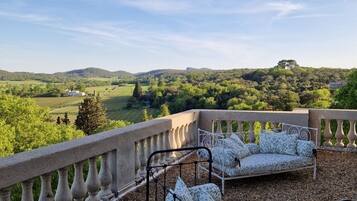 Un balcon doté d’un lit en fer forgé et d’une balustrade en pierre, offrant une vue panoramique sur un paysage magnifique.