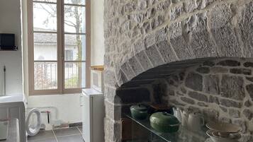 Une cuisine dotée d’une cheminée en pierre, d’une fenêtre offrant une belle vue et d’appareils électroménagers modernes.
