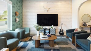 Ein Wohnzimmer mit einem an einer Holzwand montierten Flachbildfernseher, einem Couchtisch mit Büchern und Dekoration sowie zwei Sofas.