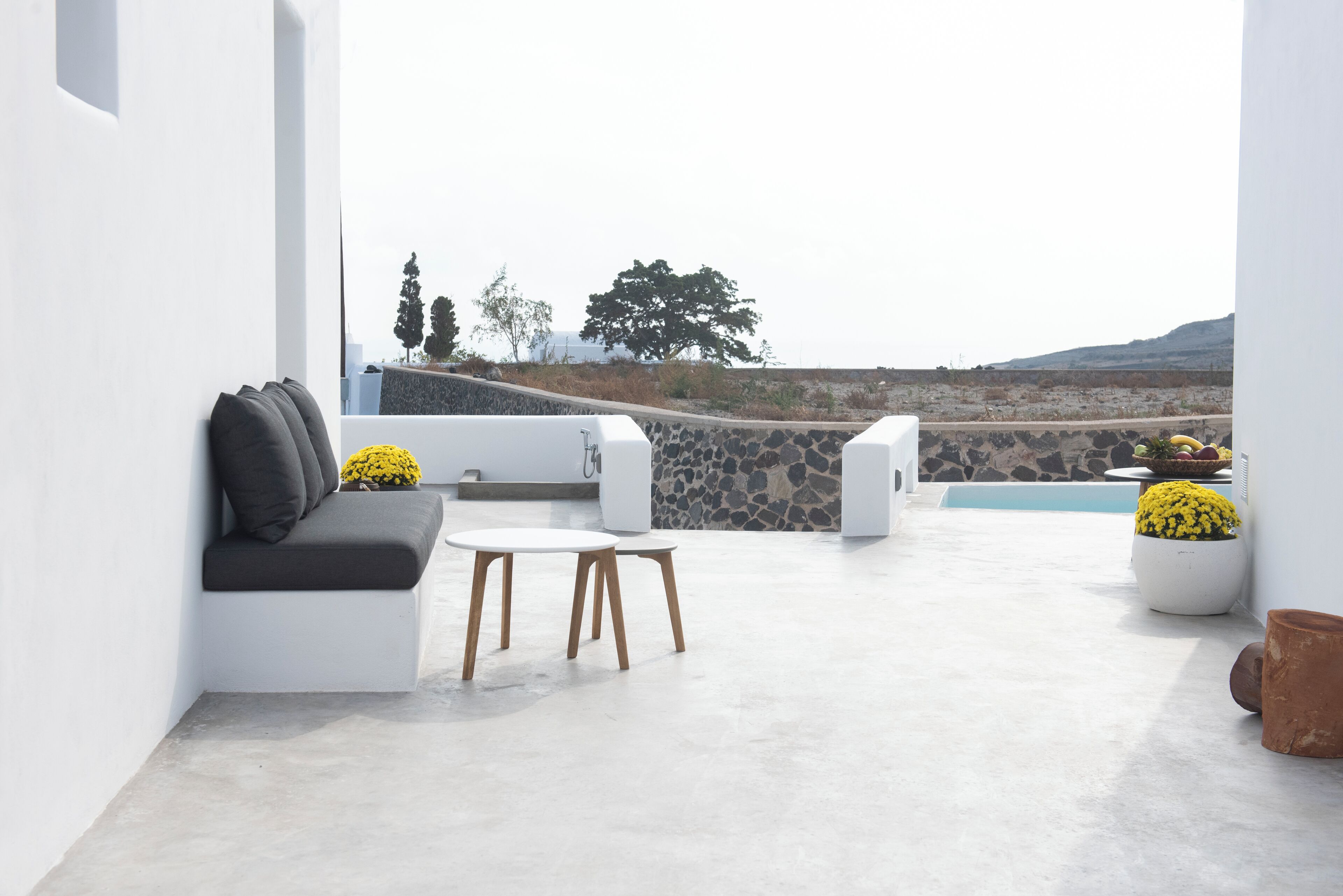 A modern outdoor seating area with a white sofa, a small table, and potted plants.