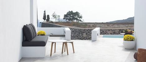 A modern outdoor seating area with a white sofa, a small table, and potted plants.