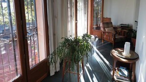 A sunlit room with a wooden chair, a small table with a plant, and a bookshelf.