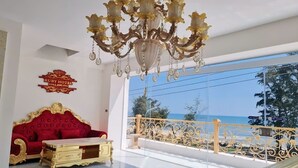 A luxurious room with a red sofa, gold furniture, and a large chandelier. -  Ruby Hotel Phan Thiet (Tien Thanh)