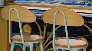 Two wooden chairs with metal frames and a potted plant on a balcony overlooking the ocean. -  Ruby Hotel Phan Thiet (Tien Thanh)