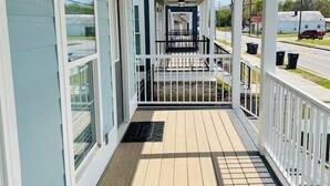A covered porch with a ceiling fan, wooden flooring, and white railings.