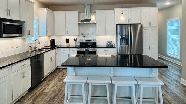 A modern kitchen with white cabinets, stainless steel appliances, and a black countertop.
