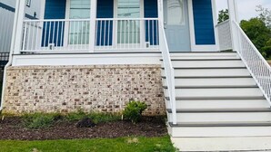 Un bâtiment à deux étages, avec une façade bleue, des balustrades blanches et des fondations en briques.