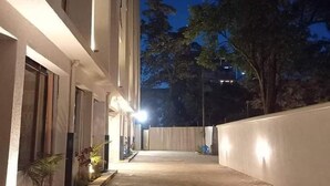 Un chemin pavé mène à un bâtiment doté d’un toit plat et d’une façade blanche.