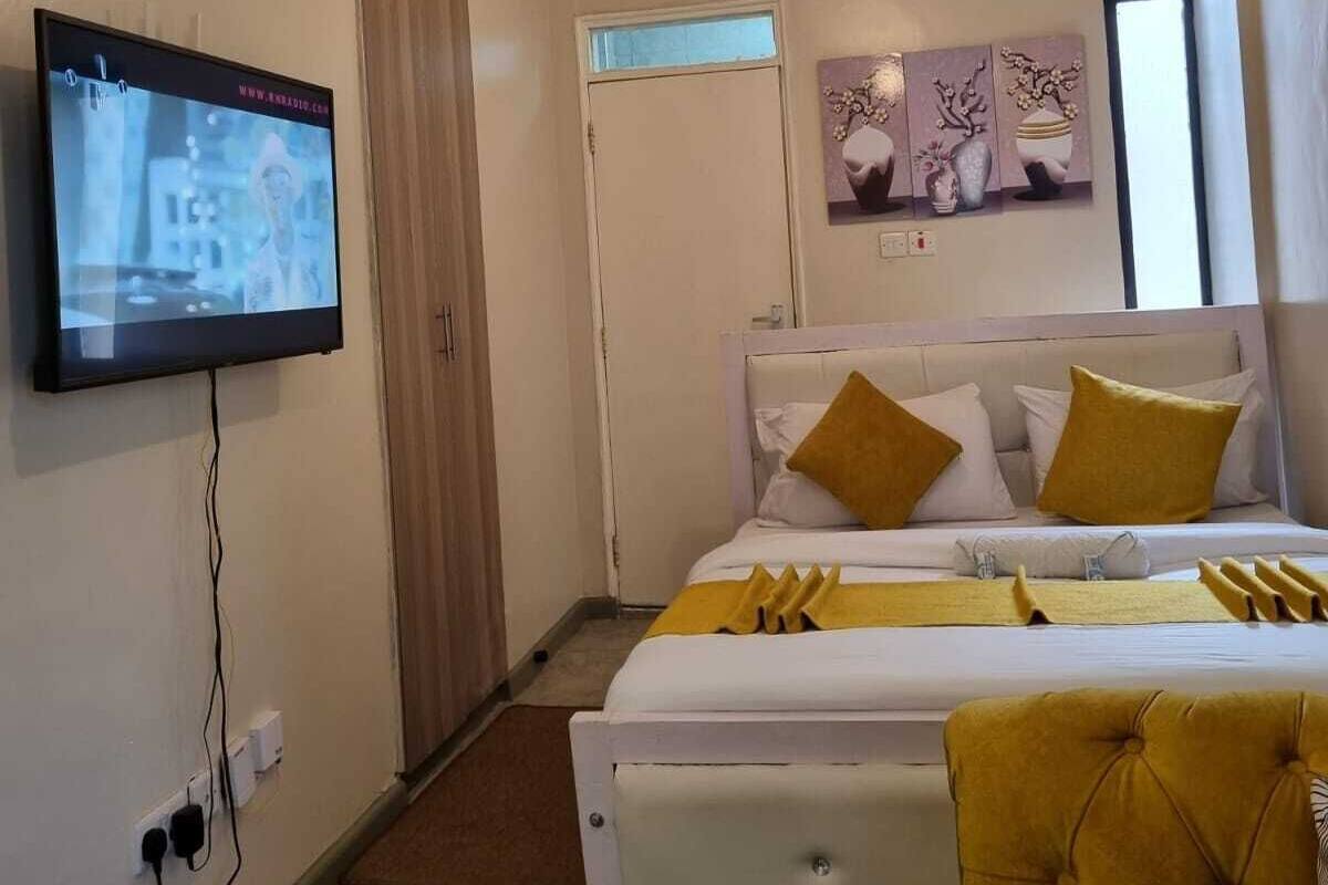 Een moderne hotelkamer met een bed, een aan de muur bevestigde televisie en een raam met gordijnen.