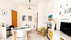 A modern living room with a dining area, a TV, and artwork on the walls. - Appartamenti Abate Riva del Golfo Home (Alcamo)