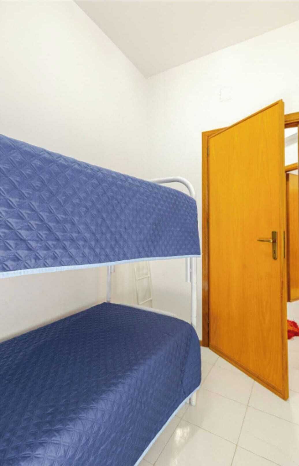 Ein Zimmer mit zwei Etagenbetten, einer Holztür und weißen Wänden.